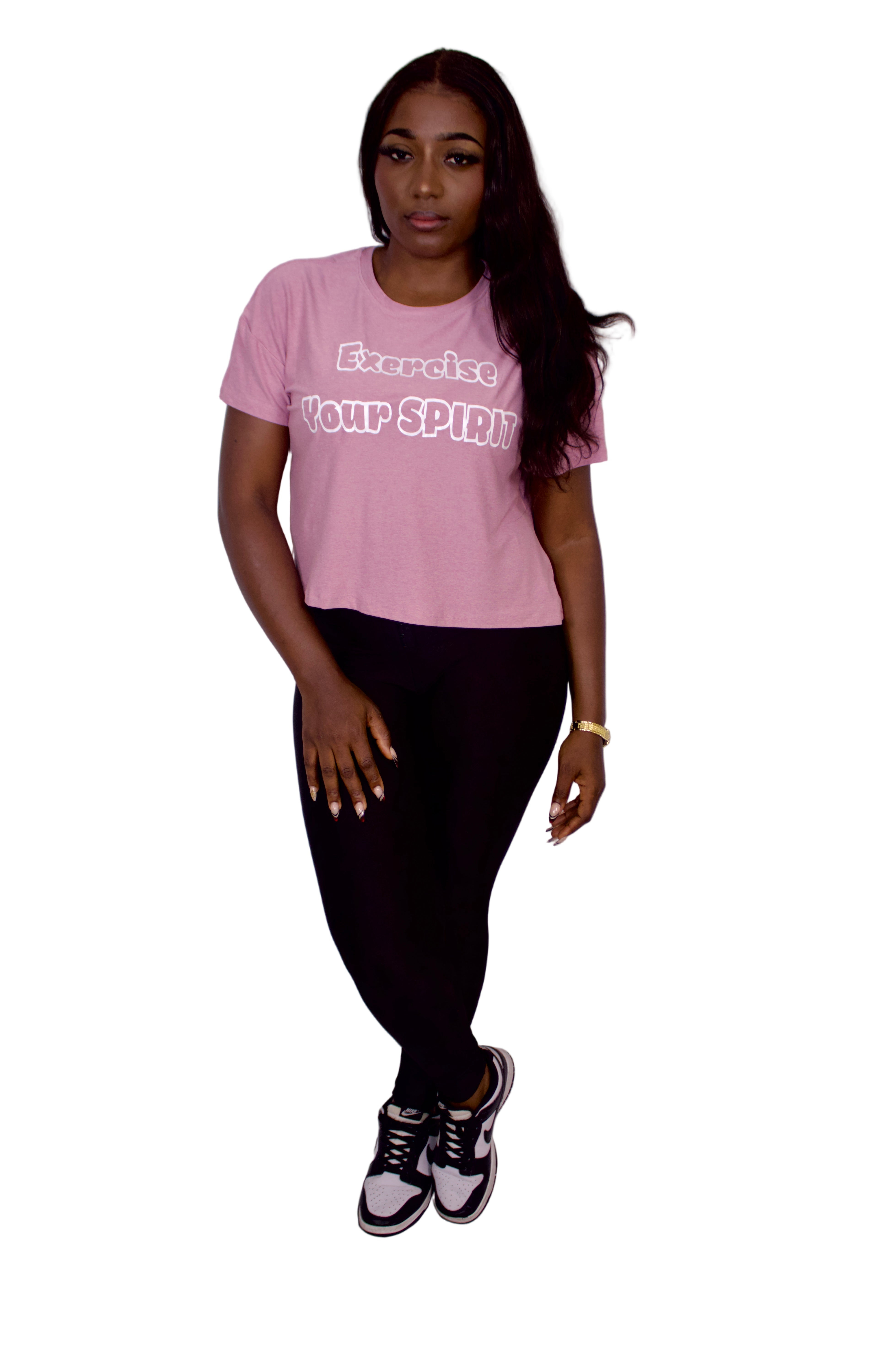 Person wearing a pink t-shirt with text and black pants on a plain background